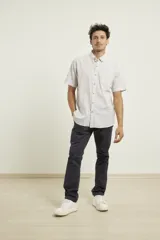 Camisa de manga corta a rayas verticales azules y blancas, con cuello abotonado y cierre frontal con botones marrones.