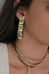 Aros colgantes largos de bronce con textura irregular.