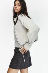 Falda pantalón de tiro medio con estampado de rayas verticales. Presenta un cinturón integrado con hebilla metálica y cierre lateral con cremallera oculta.