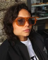 Lentes de sol unisex con montura cuadrada color naranja y cristales grises.