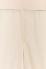 Falda midi color beige claro, de tiro alto, con cintura elástica y diseño combinado: la parte superior es opaca y la inferior es de tejido transparente o semitransparente.