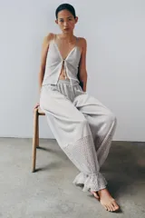 Pantalón abombacho semitransparente de tejido de encaje suave color gris, con tiro medio, cintura elástica y diseño con calados y volantes en los tobillos.