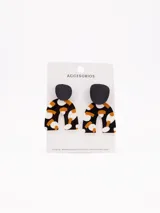 Par de aros colgantes con forma geométrica, con base superior circular negra y pieza inferior en forma de arco con estampado abstracto en tonos negro, blanco y ocre.