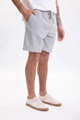 Bermuda de felpa de algodón gris melange con cintura elástica ajustable mediante cordón y bolsillos laterales.