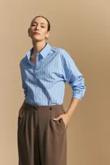 Camisa de manga larga a rayas verticales blancas y azules, con cuello camisero, cartera frontal con botones y calce relajado.