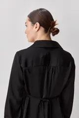 Camisa blanca de manga larga con textura suave y caída liviana, cuello camisero, puños anchos y fruncidos sutiles en los hombros.