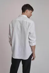Camisa blanca de lino con cuello abotonado, manga larga con puños abotonados y corte clásico.