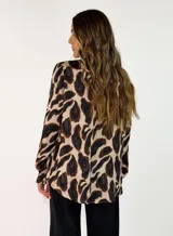 Camisa de manga larga con cuello camisero y cierre frontal de botones, confeccionada en tela fluida con estampado animal print en tonos marrones y negros.