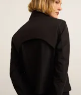 Campera deportiva negra con cuello alto, cierre frontal con cremallera y bolsillos laterales. Presenta un recorte en la espalda.