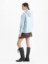 Buzo tipo hoodie color celeste, con capucha y cordones ajustables. Presenta una estampa frontal con diseño de auto con esquíes y copos de nieve, además de un logo bordado en la manga.