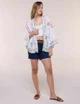 Kimono de poliéster blanco con diseño abierto, mangas amplias y bordados coloridos de motivos florales y arabescos, con terminaciones en ondas de hilo verde.
