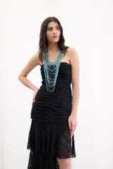 Vestido largo de encaje negro con diseño al cuerpo, escote strapless con breteles removibles, frunces frontales y falda con volados asimétricos.