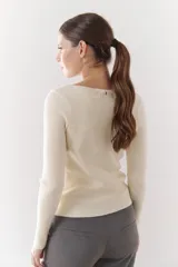 Buzo de morley color crema, con cuello bote y manga larga. Presenta un diseño de punto acanalado y un detalle de franja horizontal en el pecho.