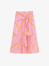 Falda larga rosada con rayas diagonales amarillas, de silueta amplia, bolsillos laterales y detalle de mangas de camisa incorporadas en la cintura para anudar.