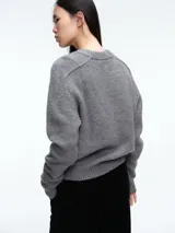 Sweater de tejido suave en tono beige melange, con cuello redondo, mangas largas y corte relajado.