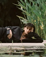 Collar con dije de forma irregular en tonos dorados y plateados, suspendido de un cordón doble de algodón negro.