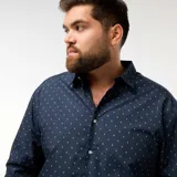 Camisa de corte recto y manga larga en color azul marino, con estampado de pequeños motivos blancos. Presenta cuello clásico y cierre frontal con botones.