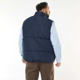 Chaleco acolchado tipo puffer en color azul marino, confeccionado en tejido repelente al agua. Presenta cuello alto, cierre frontal con cremallera y botones a presión, y bolsillos delanteros de parche.