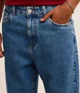 Pantalon de jean gris con lavado deslavado, de corte baggy y silueta holgada. Cuenta con bolsillos al frente y atras, y cierre de boton y cremallera.