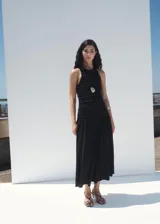 Vestido midi negro sin mangas, con cuello redondo y diseño ajustado en el torso mediante fruncidos laterales, que se abre en una falda evasé fluida.