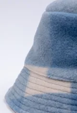 Gorro tipo bucket de textura peluda, con estampado a cuadros en tonos azules y beige.