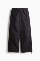 Pantalón cargo de corte holgado en color negro, con múltiples bolsillos laterales con solapa, pliegues en las rodillas y cordones ajustables en el bajo.