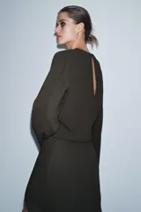 Vestido midi de Zara Woman Collection, color verde oscuro, con cuello redondo, manga larga y detalle de pliegues en el delantero. Presenta un corte recto con abertura frontal en el bajo y cierre lateral con cremallera oculta.