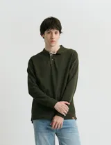 Remera de punto canalé francés color verde militar, con cuello polo, manga larga y cierre frontal con botones de madera. Presenta detalles a contratono en la cartera interna.