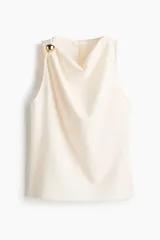 Musculosa en punto de crepé color marfil, sin mangas, con escote drapeado y detalle de aplicación metálica dorada en el tirante derecho.