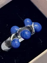 Anillo artesanal de vidrio transparente con diseño irregular y esferas de color azul intenso incrustadas.