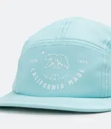 Gorra celeste de cinco paneles con ala recta y estampado frontal con un oso y la leyenda "California Made".