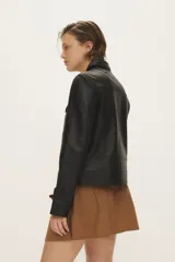 Campera de cuero negro al cuerpo, con cuello camisero, bolsillos de parche con solapa en el pecho y cierre frontal con broches a presión.
