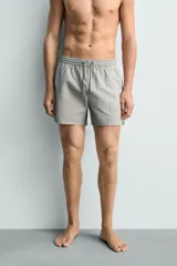 Short de baño confeccionado en tejido técnico con patrón de rayas verticales en tonos azul marino y blanco, con cintura elástica ajustable mediante cordón y bolsillos laterales.