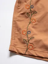 Short de baño azul marino con bordado de enredadera en la pierna izquierda. Tiene cintura elástica con cordón regulable, bolsillos laterales y trasero con cierre, y suspensor de malla fina hipoalergénico.