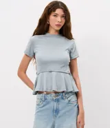 Blusa de punto Roma color celeste, con cuello alto, mangas cortas y diseño peplum. Presenta recortes estructurales y un cinturón integrado con hebilla metálica en la cintura, finalizando en un ruedo con volados.