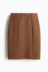 Pollera ajustada de punto color marrón, con tiro alto y elástico oculto en la cintura. Modelo a la rodilla con costuras visibles en el frente y tajo en la parte trasera.