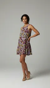 Vestido corto con estampado floral multicolor en tonos violetas, amarillos y rosados. Tiene escote halter, bolsillos laterales y corte suelto.