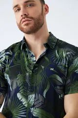 Camisa de manga corta con estampado botánico de hojas en tonos azul y blanco. Presenta cuello clásico, cierre frontal abotonado y corte slim.