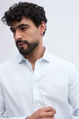 Camisa de manga larga fit semi slim color celeste, con cierre frontal de botones y cuello camisero clásico.