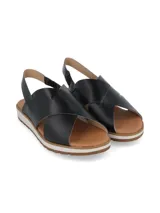 Sandalia de cuero negro con tiras cruzadas en el empeine y tira trasera con elástico. Cuenta con una suela plana de plataforma bicolor, blanca y marrón, con base dentada.