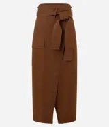 Pollera midi marrón de corte evasé, confeccionada en sarga de algodón. Presenta cintura con trabillas, cinturón con lazo, bolsillo cargo con solapa y encaje delantero.