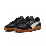 Championes Puma modelo Palermo LTH, con diseño de perfil bajo, cuerpo de cuero blanco, detalles en gamuza gris y franja lateral en color lila. Cuenta con suela de goma color caramelo y logo dorado en el lateral.