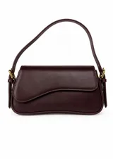 Cartera de hombro de diseño estructurado y minimalista, color bordó, con solapa frontal asimétrica y herrajes metálicos dorados. Incluye dos correas intercambiables, una corta para llevar al hombro y una larga ajustable para usar cruzada.