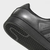 Championes Adidas Superstar II, modelo clásico de caña baja en color plateado metalizado con detalles en negro, incluyendo las tres tiras icónicas, los cordones, la suela y el refuerzo del talón. Cuentan con la tradicional puntera de caucho con relieve y exterior de cuero.