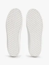 Zapatillas de corte bajo Tommy Hilfiger confeccionadas en piel napa de color blanco. Presentan un diseño clásico con cordones, panel metalizado en el talón y logos de la marca grabados en relieve en el lateral, la lengüeta y el talón. La suela es de goma vulcanizada.