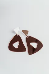 Aros colgantes de acrílico con forma geométrica abstracta. El gancho superior es un pequeño triángulo blanco, y la pieza principal es un triángulo grande con un hueco interior de forma irregular, ambos con acabado espejado color oro rosa.