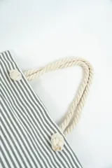 Bolso de tela tipo tote bag con estampado de rayas horizontales azules y blancas, y base de color beige. Tiene asas de cuerda de color beige.