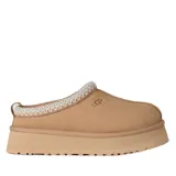 Zuecos UGG modelo Tazz de gamuza color beige, con plataforma alta y detalle de costura trenzada en el borde superior. Presenta el logo de la marca grabado en el lateral.