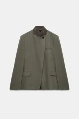 Blazer de corte estructurado en color verde oliva, con cuello subido en tejido a contraste de textura aterciopelada. Presenta cierre frontal con un solo botón, bolsillos con solapa en el delantero y un bolsillo superior tipo ojal.
