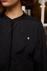Camisa de nylon color bordó, de corte holgado y diseño minimalista con mangas largas abullonadas y puños elásticos.